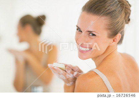 Portrait of smiling young woman washing hands with soap 16726546