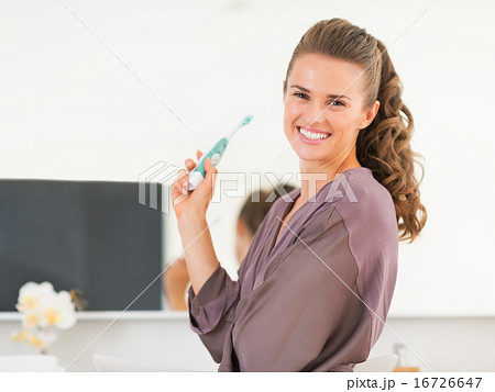 Happy young woman brushing teeth in bathroom 16726647
