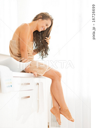 Young woman with long wet hair sitting in bathroom 16726699