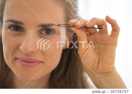 Portrait of happy young woman tweezing eyebrows Portrait of happy young woman tweezing eyebrows 16726737