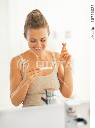 Happy young woman looking on pregnancy test waiting for good new 16726825