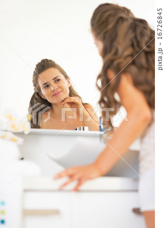 Portrait of happy young woman checking facial skin condition Portrait of happy young woman checking facial skin condition 16726845