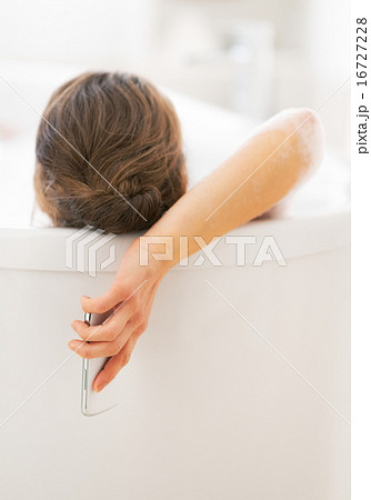 Young woman with cell phone laying in bathtub. rear view Young woman with cell phone laying in bathtub. rear view 16727228