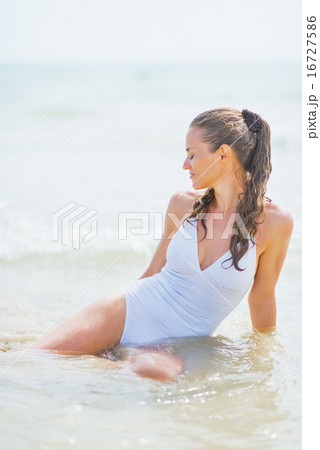 Young woman sitting on sea coast 16727586