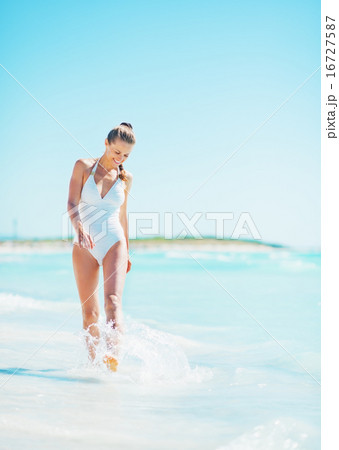 Full length portrait of smiling young woman walking at seaside Full length portrait of smiling young woman walking at seaside 16727587