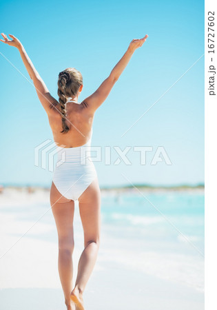 Young woman rejoicing on beach. rear view 16727602