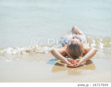 Young woman in swimsuit laying on sea shore. rear view 16727609