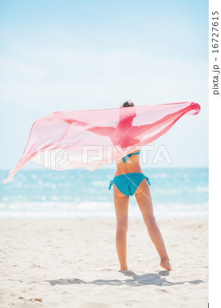 Young woman with parero rejoicing on beach. rear view 16727615