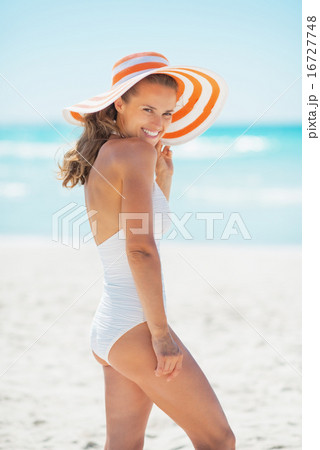 Smiling young woman in hat standing on beach Smiling young woman in hat standing on beach 16727748