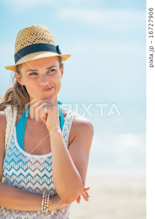 Portrait of thoughtful young woman in hat on beach 16727906