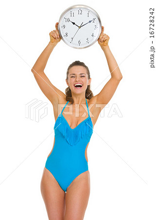 Smiling young woman in swimsuit showing clock Smiling young woman in swimsuit showing clock 16728242