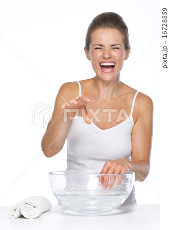 Happy young woman making fun while washing hands in glass bowl w 16728859