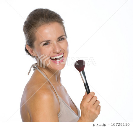 Portrait of smiling young woman with makeup brush Portrait of smiling young woman with makeup brush 16729110