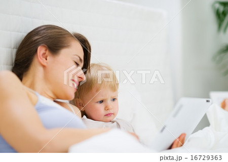 Young mother showing baby something in tablet PC Young mother showing baby something in tablet PC 16729363