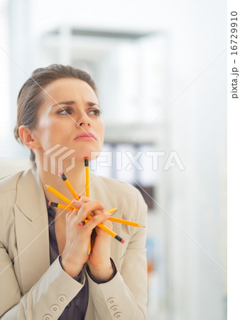 Portrait of thoughtful business woman holding pencils 16729910