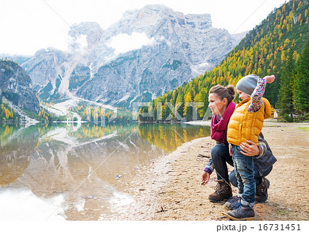 Mother and baby throwing stones on lake braies in south tyrol, i 16731451