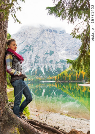 Full length portrait of young woman standing near tree on lake b 16731452