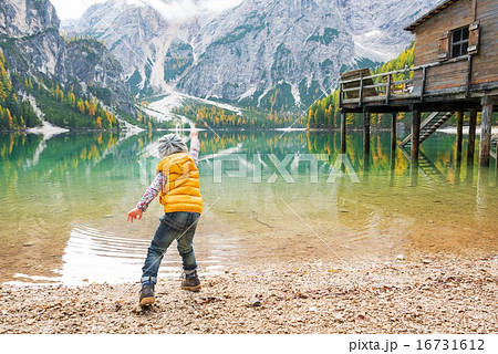 Child throwing stones on lake braies in south tyrol, italy. rear 16731612