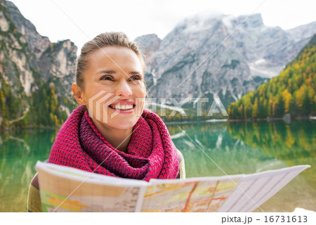 Portrait of happy young woman with map on lake braies in south t 16731613