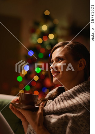 Thoughtful woman sitting chair and drinking hot beverage in fron 16731621