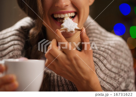 Closeup on happy woman eating Christmas cookie in front of Chris Closeup on happy woman eating Christmas cookie in front of Chris 16731622