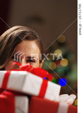 Happy young woman holding christmas present boxes in front of fa 16731796