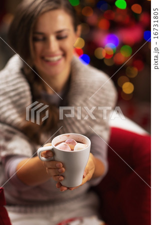 Closeup on cup of hot chocolate with marshmallow in hand of smil Closeup on cup of hot chocolate with marshmallow in hand of smil 16731805