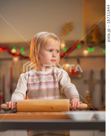 Portrait of baby ro   lling pin dough in christmas decorated kitche
