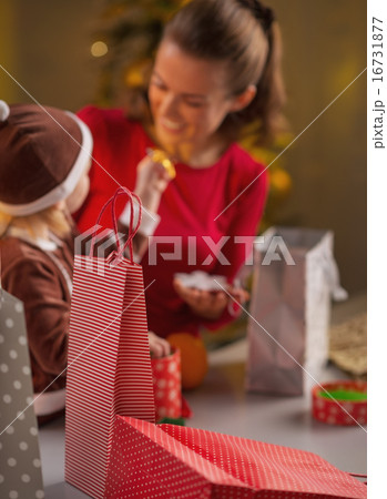 Closeup on christmas shopping bags and mother and baby in backgr 16731877