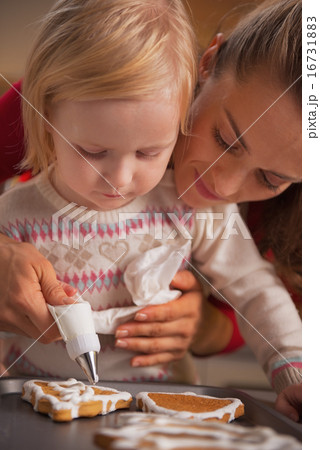 Mother and baby decorating homemade christmas cookies with glaze 16731883