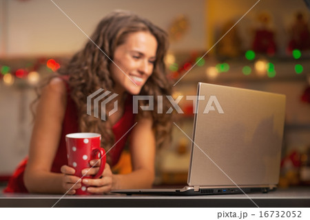 Closeup on laptop and happy young woman with cup of hot chocolat 16732052