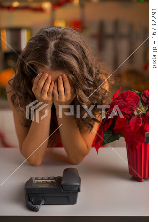Stressed young housewife near phone in christmas decorated kitch 16732291