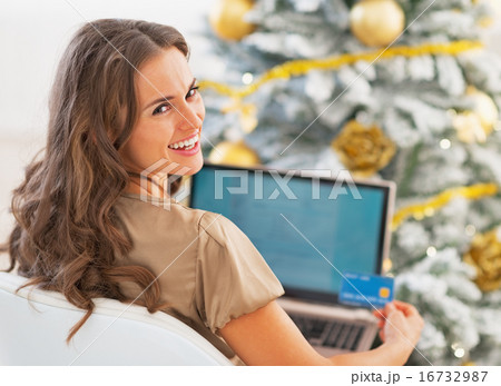 Portrait of smiling young woman with credit card and laptop in f 16732987