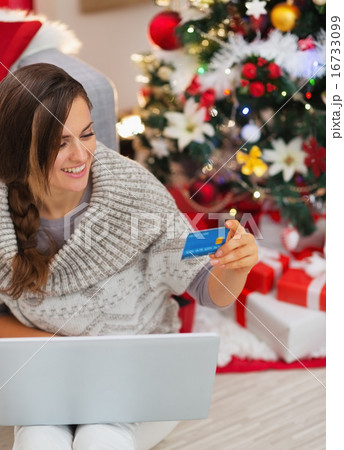 Smiling woman with laptop and credit card near Christmas tree Smiling woman with laptop and credit card near Christmas tree 16733099