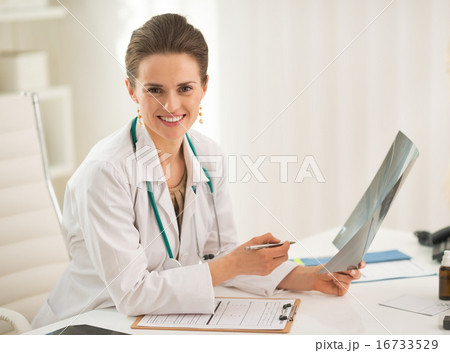 Portrait of happy doctor woman holding fluorography in office 16733529