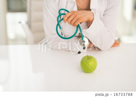 Closeup on medical doctor woman with stethoscope and apple Closeup on medical doctor woman with stethoscope and apple 16733788