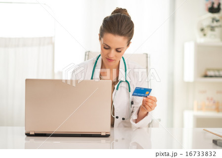 Medical doctor woman with credit card using laptop Medical doctor woman with credit card using laptop 16733832