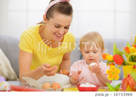 Happy mother and baby eating Easter eggs Happy mother and baby eating Easter eggs 16733966