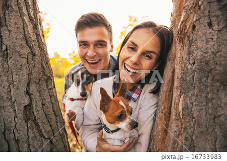 Portrait of happy young couple with dogs outdoors in autumn park Portrait of happy young couple with dogs outdoors in autumn park 16733983