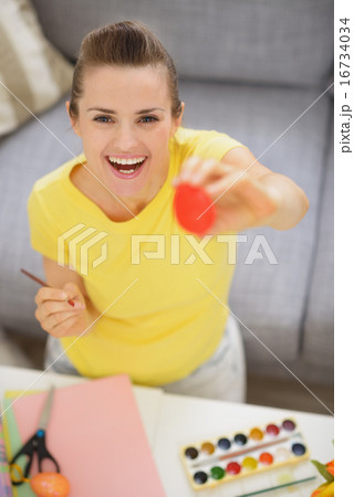 Smiling young woman showing Easter red egg 16734034