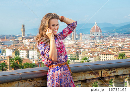 Happy young woman talking cell phone against panoramic view of f Happy young woman talking cell phone against panoramic view of f 16735165
