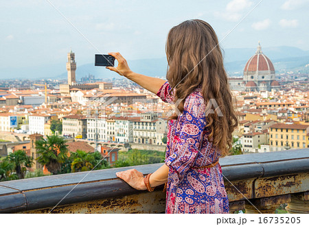 Smiling young woman taking photo of panoramic view of florence, 16735205