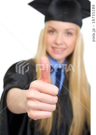 Closeup on young woman in graduation gown showing thumbs up Closeup on young woman in graduation gown showing thumbs up 16735289