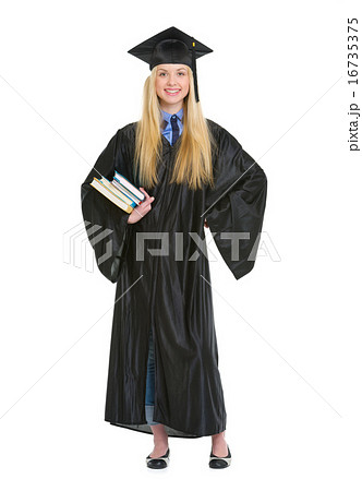Full length portrait of young woman in graduation gown with book Full length portrait of young woman in graduation gown with book 16735375