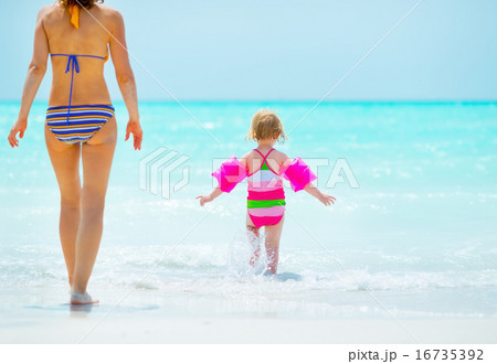 Mother and baby girl going into sea. rear view Mother and baby girl going into sea. rear view 16735392