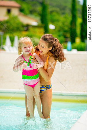 Happy mother and baby girl playing in swimming pool 16735599
