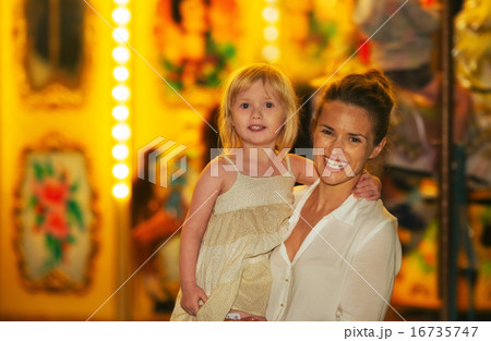 Portrait of happy mother and baby girl in front of carousel 16735747