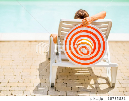 Young woman with hat laying on chaise-longue. rear view 16735881