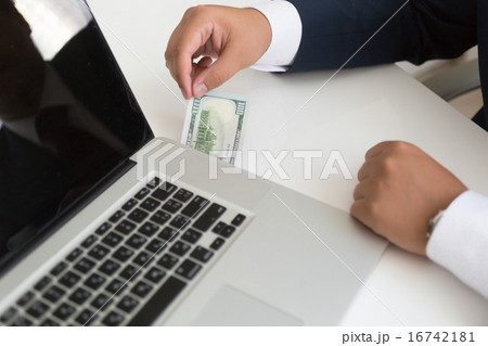 man in suit inserting dollar bill in the laptop 16742181