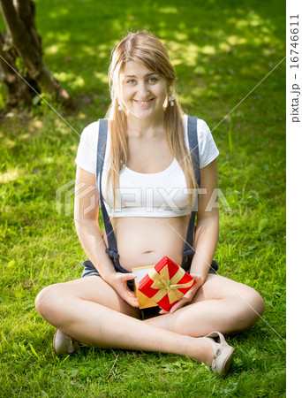 pregnant woman relaxing at park and holdi gift box pregnant woman relaxing at park and holdi gift box 16746611